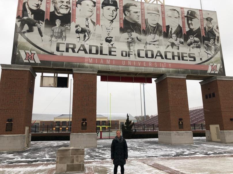 Assistant Field Hockey Coach Rayell Heistand stands in front of Miami’s all-male Cradle of Coaches at Yager Stadium. Photo by Emily Goliver