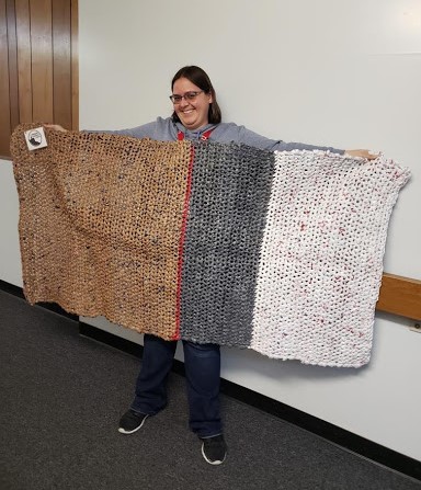  Karissa Uhl holds up a mat made of plastic grocery bags. Volunteers need about 800 bags to crochet one six-foot long mat. Photo courtesy of Karissa Uhl