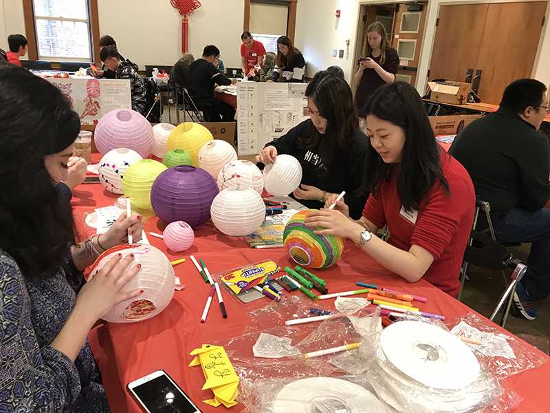 Students Olivia Lewis (left) and Tian Qi decorate paper lanterns with visiting international instructor Wenting Yang (far right). Photo by Erin Glynn