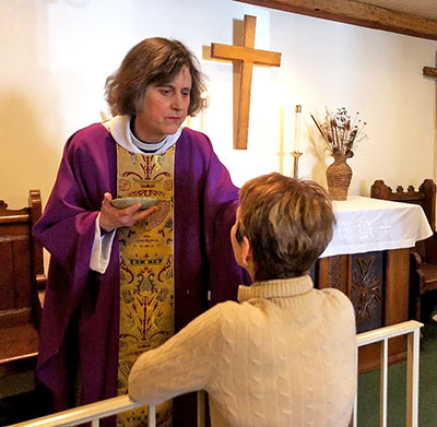 Reverend Sara Palmer at Holy Trinity Episcopal Church spreads the ashes on congregation member Ellen Reister’s forehead after the Ash Wednesday service on March 6. <em>Photo by Leanne Stahulak.</em>