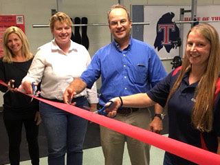 Officers in the Talawanda Athletic Boosters Angie James, Bonnie Norris and Dave Krausher join Talawanda Middle School Athletic Director Annie Klenk in cutting the ribbon to dedicate the middle school fitness and weight room in 2018. Photo courtesy of the Talawanda Athletic Boosters‍