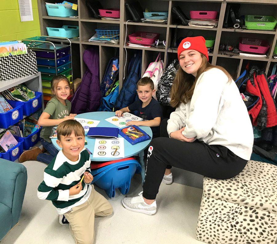 First graders at Kramer Elementary (left to right) Jazzy Virk Tiago Motta and John Cerillo, learn Spanish phrases from Chloe Newsom, a student in a Miami conversational Spanish class. Photo by Aaron Smith