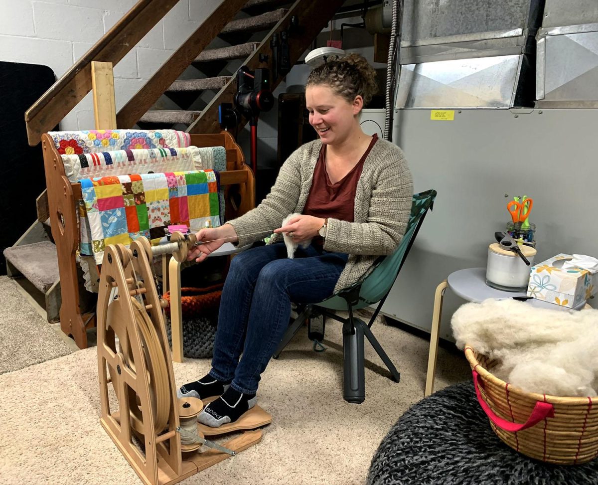 McQuigg spinning yarn on her wheel. A largely self-taught “fiber artist,” she says she works “sheep to sweater.” Photo by Lexi Scherzinger