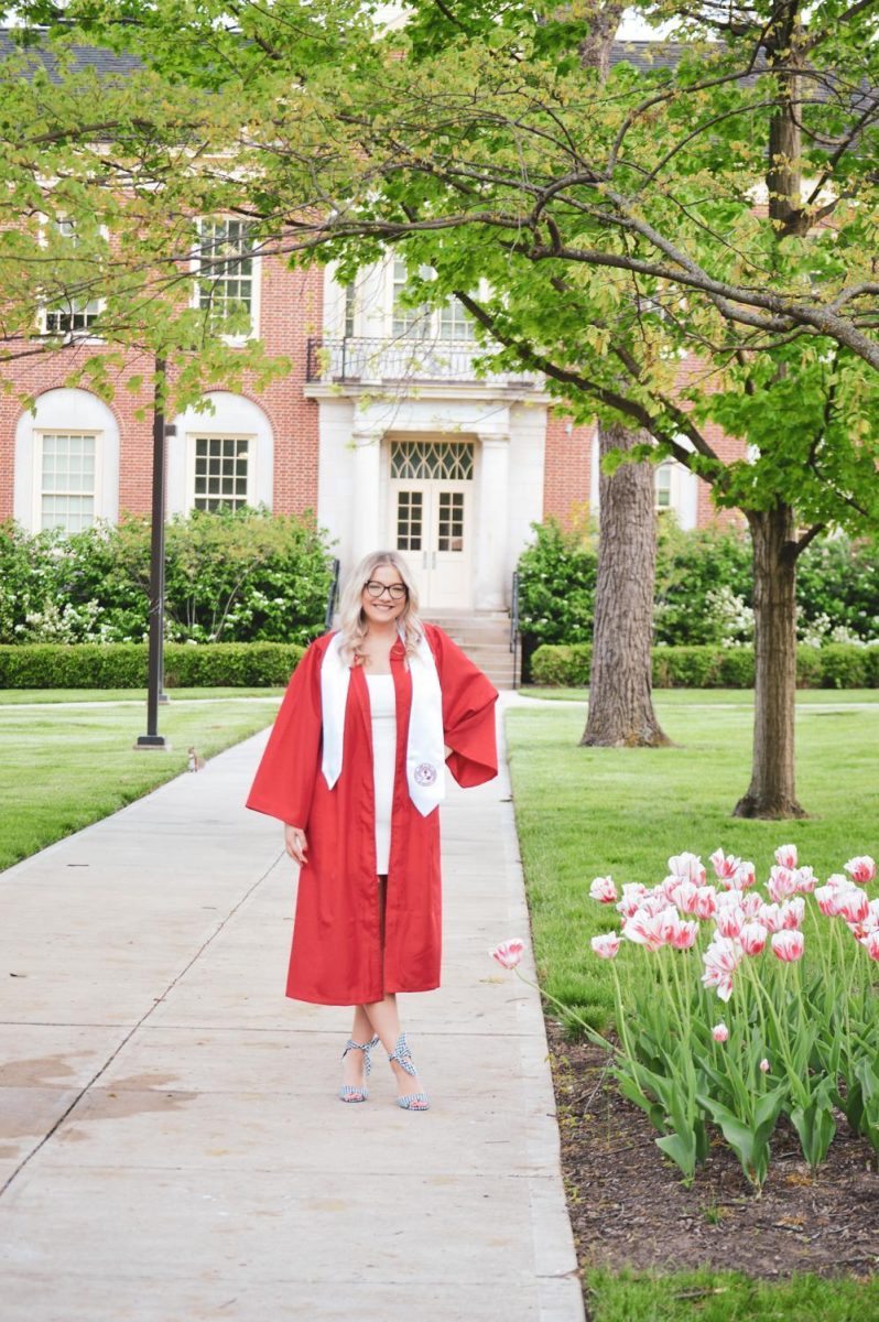 Halie Barger, a graduating Miami senior and member of the Observer staff, seen here in front of Kreger Hall, was one of many students who donned graduation robes and posed for a final school picture on campus this week. Photo provided by Halie Barger