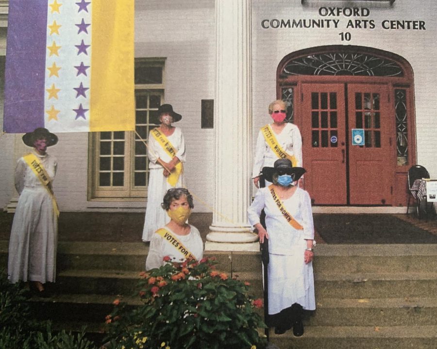League of Women Voters members in period costume pose at the Oxford Community Arts Center in front of the 19th Amendment ratification flag:  (front row) Kathy McMahon-Klosterman, Jo McQueen, Toni Saldivar; (back row): Linda Simmons, Becky Quay. Photo provided by the League of Women Voters