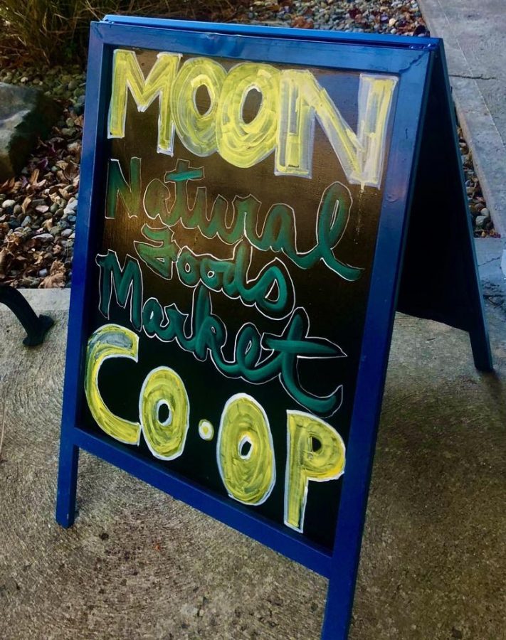 The sidewalk sign board welcomes passerby into MOON Co-Op. Photo by Camryn Smith