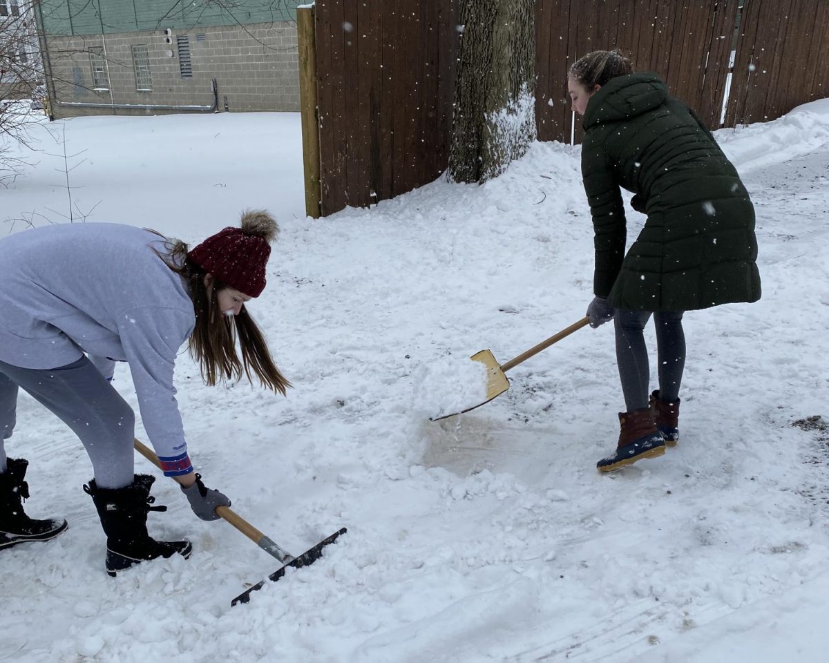 Emily Stegmeyer (left) and Shannon Allen shovel out Thursday morning at their house on Church Street.