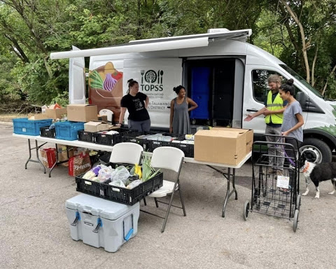 Oxford City Councillor Chantel Raghu (right with dog) and Ross Olson,  marketing co-coordinator for the Farmers Market and the TOPSS mobile food pantry, and other volunteers, at the van’s set-up spot at the Park View Arms apartments on Oxford’s west side.