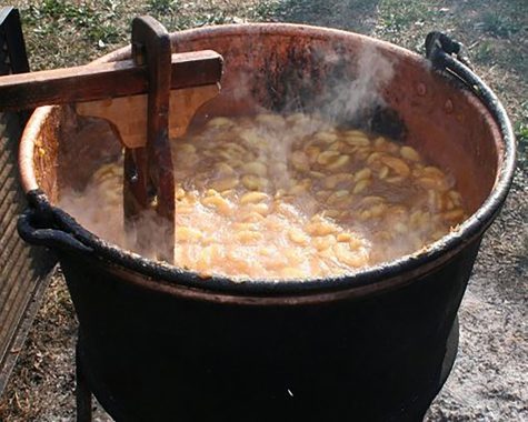 In this scene from the 2019 festival, apple butter is cooked the pioneer way, simmered and stirred in a huge copper kettle. 
