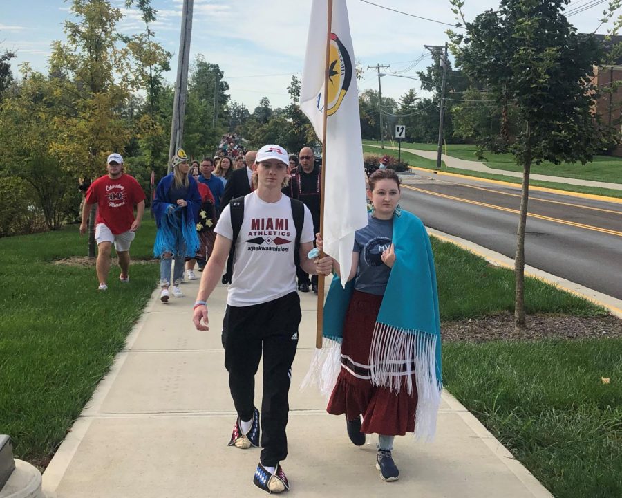 Senior Josh McCoy and Junior Emma Fanning, both Myaamia Heritage students, carry the Miami Tribe flag, leading the walk of reflection.