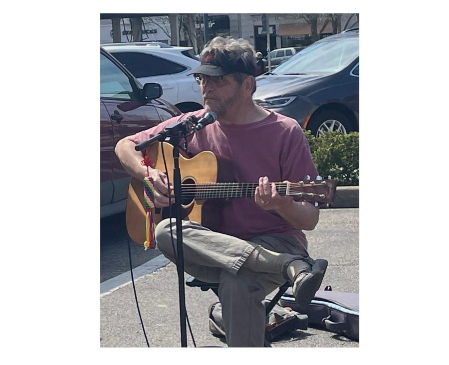 Dave Sams strums a tune to help provide a musical atmosphere at the Oxford Farmers Market. 