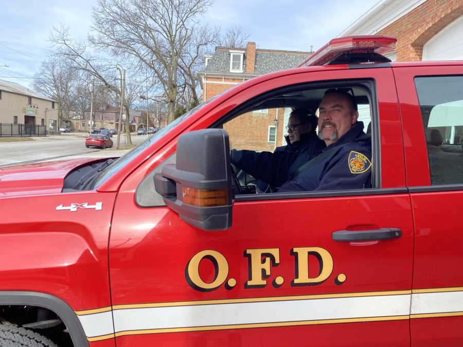 Captain Chris Johns (front) and Fire Chief John Detherage (back) ride in a truck. They help lead the department. 