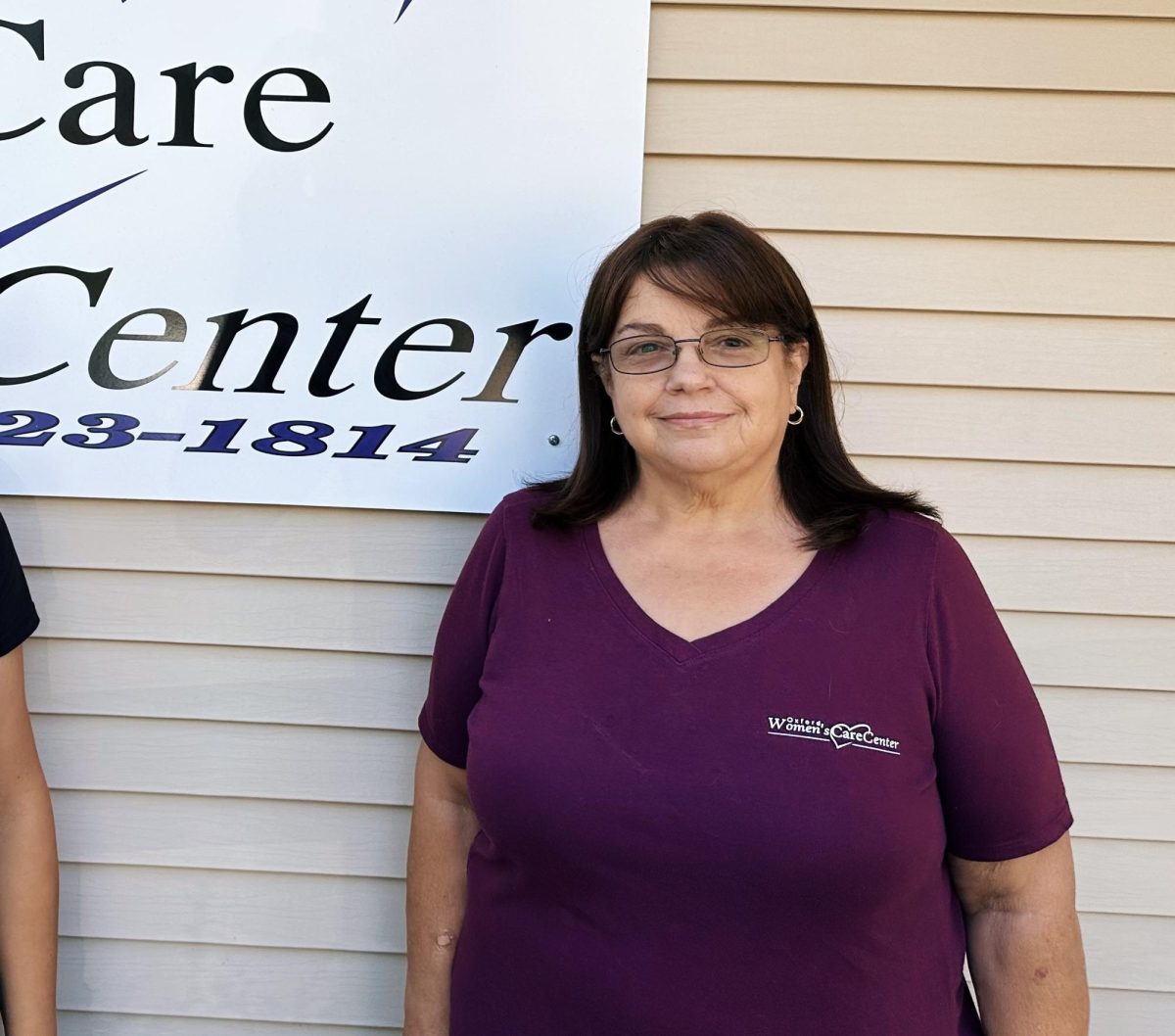 Treena Newcomer smiles in front of the womens care center sign. 