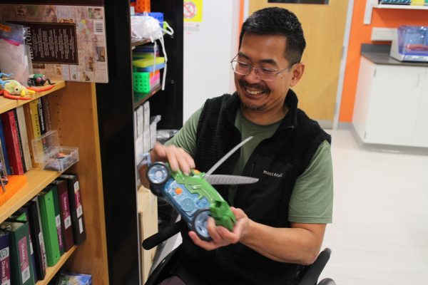 Yoshi Tomoyasu laughs as he shows off a childrens  toy he uses in lecture demonstrations.