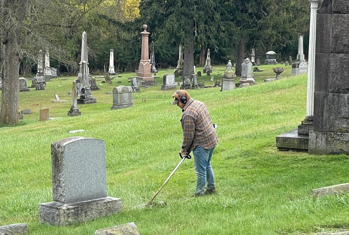 Seasonal cemetery maintenance worker Blake Detherage uses a weed eater to cut grass closer to tombstones. Photo provided by Mike Green.