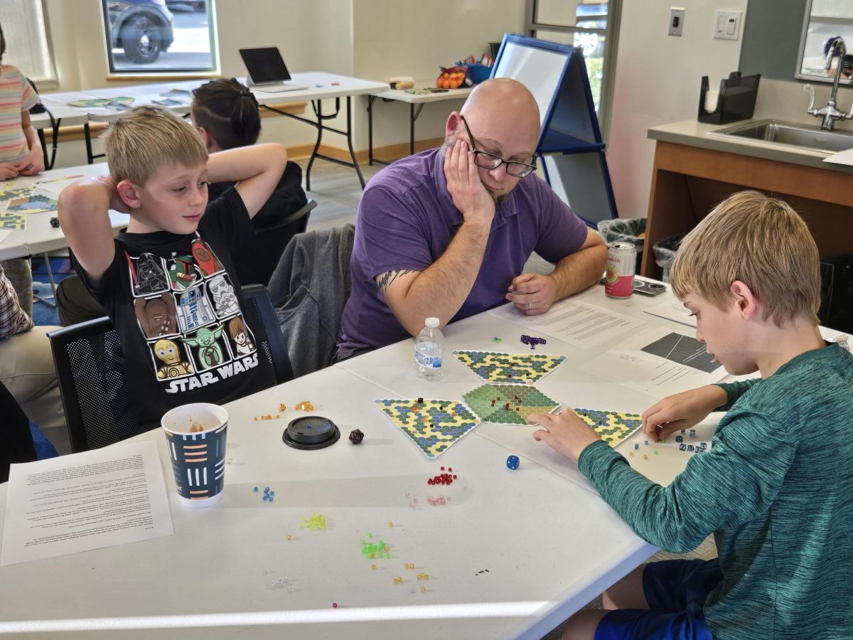 Joe Hawkins and his two sons chose to play “Ablaze.” Each game features an element of luck with random “climate factor” cards that can either help or hinder the players. The Hawkins family was lucky and drew the “Rainy Season” card, stopping the spread of the fire and leading them to a swift victory. Photo by Diego Smith