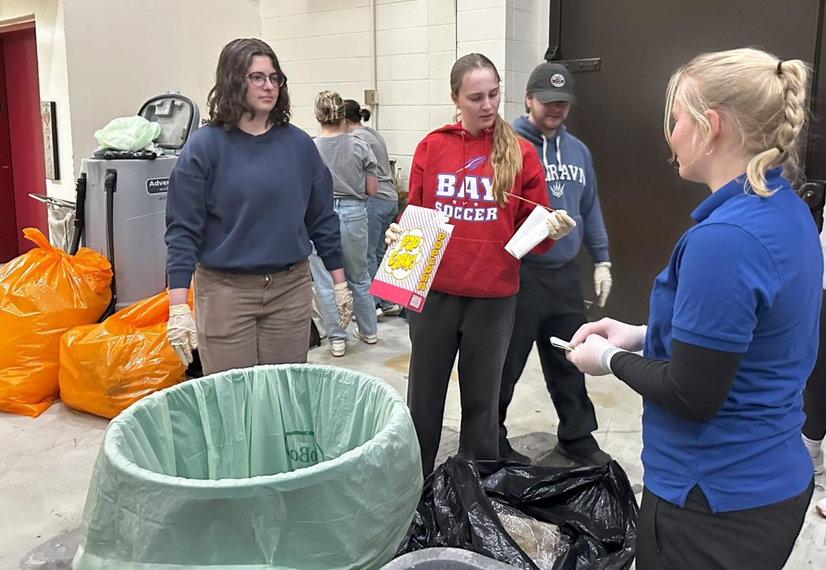  Student volunteers open trash bags and remove waste like popcorn boxes from waste bags into recycling bins. Photo by Grace Grover.
