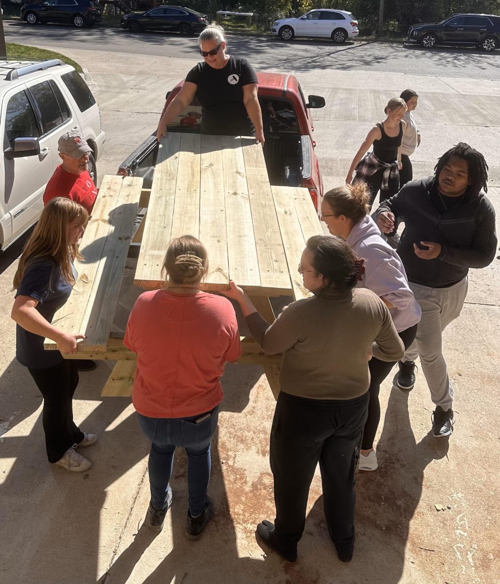 Service+ members load a picnic table they built during a life skills event onto a truck.