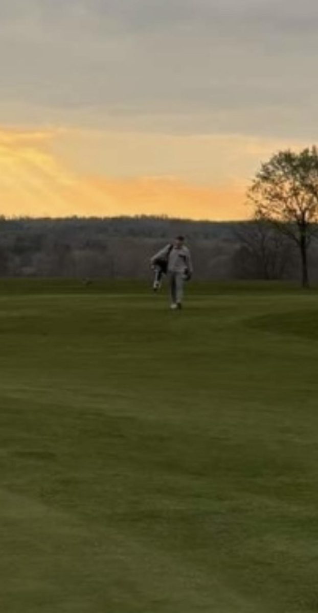 Samson Mingione walks to the ball he just hit while carrying his golf bag. Over the past two years, Mingione has become a regular at the club, making an attempt to go whenever he can. He has played golf for four years total, starting during COVID. Photo by Cameron Johnson